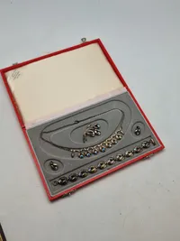 Smykkesæt bestående af halskæde, armbånd, øreringe og broche. Sættet er af sterlingsølv med isatte sten. Designet af Hans Siersbøl