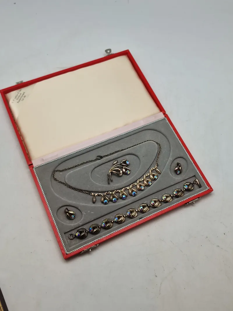Smykkesæt bestående af halskæde, armbånd, øreringe og broche. Sættet er af sterlingsølv med isatte sten. Designet af Hans Siersbøl