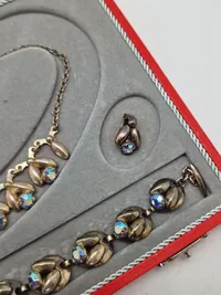 Smykkesæt bestående af halskæde, armbånd, øreringe og broche. Sættet er af sterlingsølv med isatte sten. Designet af Hans Siersbøl