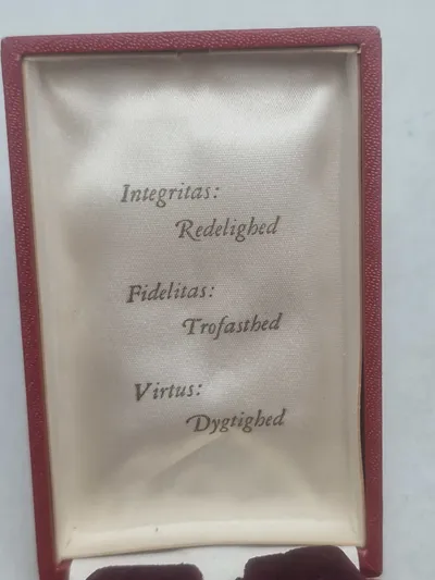 Medaljeæske med teksten i låget: Integritas: Redelighed - Fidelitas: Trofasthed - Virtus: Dygtighed + rødt/hvidt medaljebånd