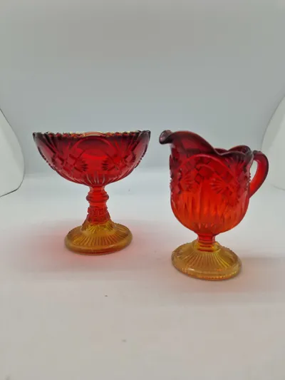 Glas opsats og kande fra Fyens Glasværk, opsatsen og kanden er i presset glas. Skålen, på opsatsen, er rød og stilken er gul, farverne fader ud fra rød til gul