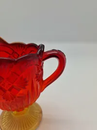 Glas opsats og kande fra Fyens Glasværk, opsatsen og kanden er i presset glas. Skålen, på opsatsen, er rød og stilken er gul, farverne fader ud fra rød til gul
