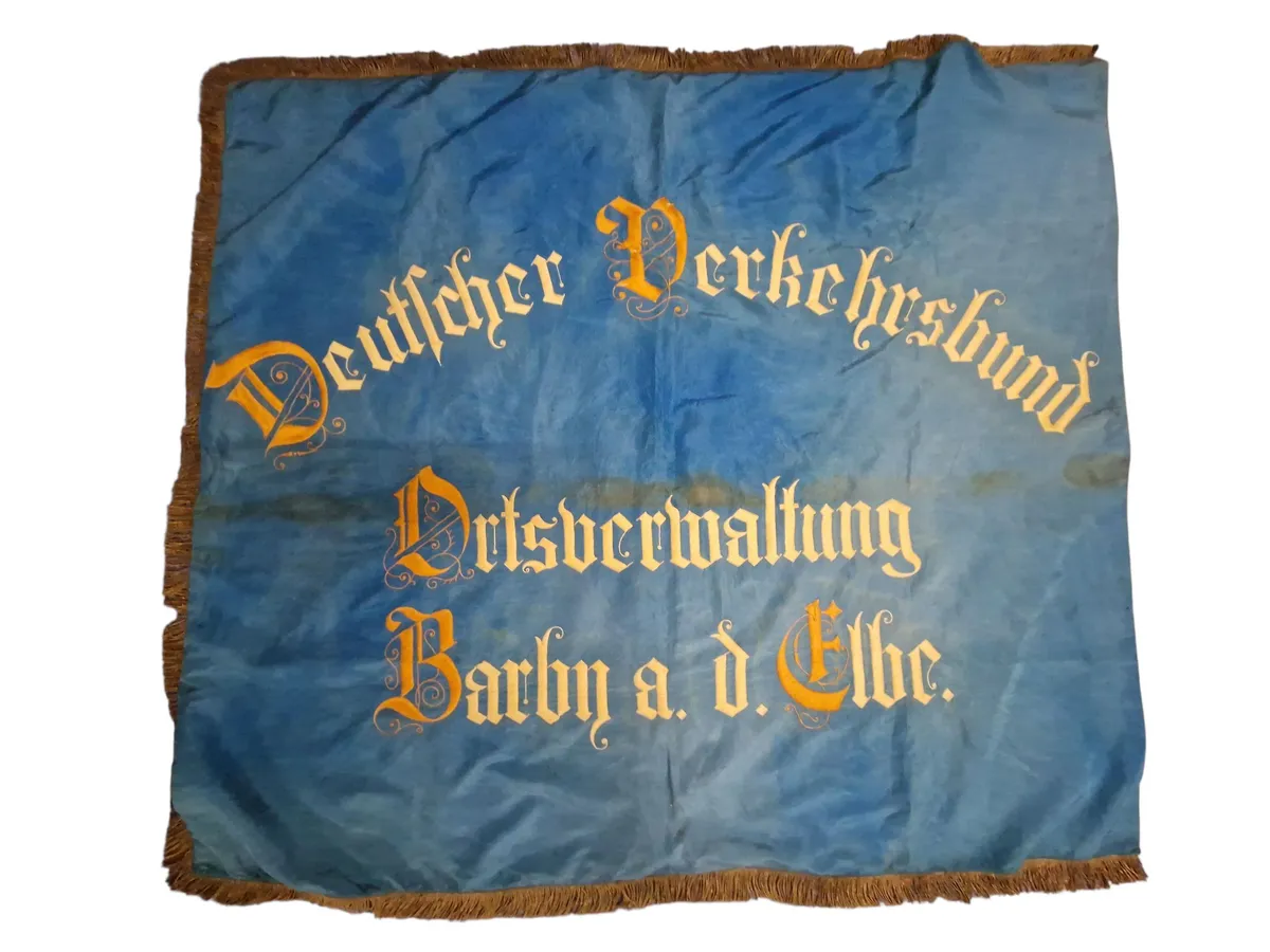 Originalt Tysk WW1 blå fane med teksten "Deutscher Verkehrsbund Ortsverwaltung Barby a. d. Elbe." broderet med gul skrift.