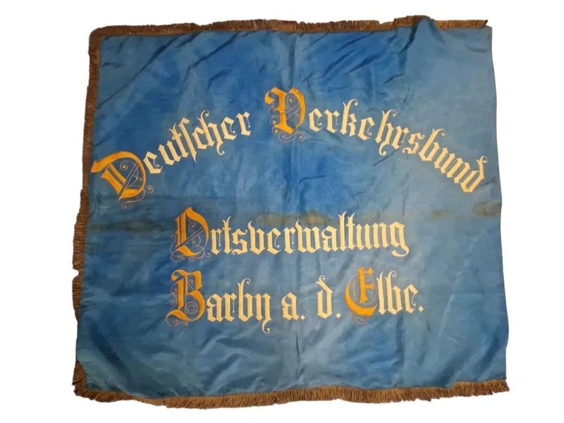 Originalt Tysk WW1 blå fane med teksten "Deutscher Verkehrsbund Ortsverwaltung Barby a. d. Elbe." broderet med gul skrift.