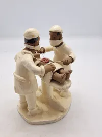 Sjælden Skulptur som forestiller to læger, der udfører en operation, og er skabt af den brasilianske folkekunstner Amaro Rodrigues