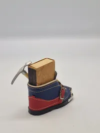 miniature af en skistøvle, der fungerer som en holder til en æske tændstikker og en lille ishakke.