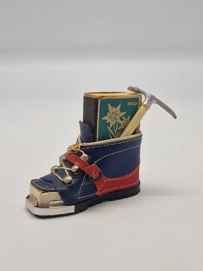 miniature af en skistøvle, der fungerer som en holder til en æske tændstikker og en lille ishakke.