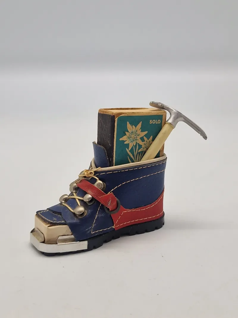 miniature af en skistøvle, der fungerer som en holder til en æske tændstikker og en lille ishakke.