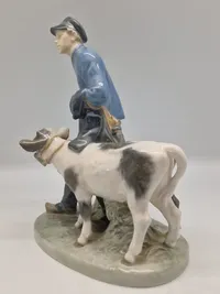 Royal Copenhagen figur kaldet "Dreng med Kalve" eller "Bondedreng m/ kalve", med nummer 1858. Figuren er designet af Christian Thomsen.