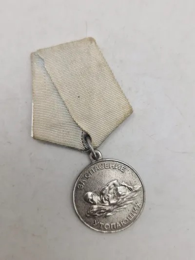 Original sovjetisk medalje kendt som "Medal for Saving the Drowning" (Медаль «За спасение утопающих»).
