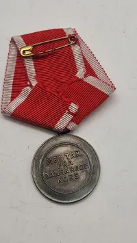 Dansk Røde Kors Fortjenstmedalje, som blev indstiftet i 1927 og tildeles for fortjenstfuld indsats for Røde Kors. Original