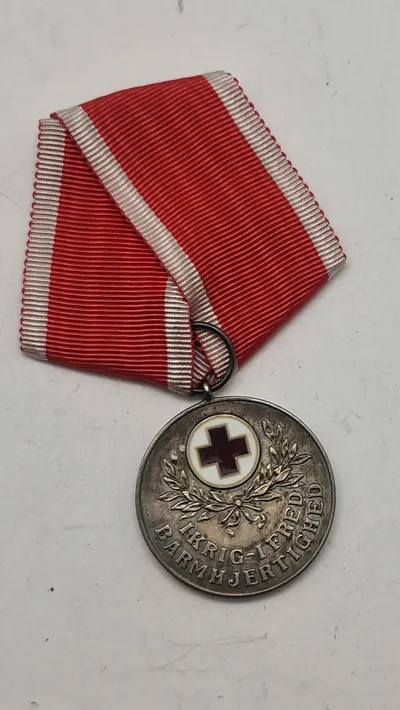 Dansk Røde Kors Fortjenstmedalje, som blev indstiftet i 1927 og tildeles for fortjenstfuld indsats for Røde Kors. Original