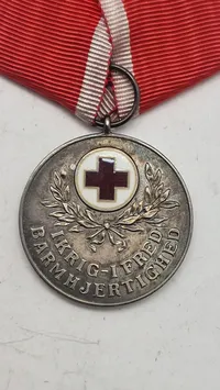 Dansk Røde Kors Fortjenstmedalje, som blev indstiftet i 1927 og tildeles for fortjenstfuld indsats for Røde Kors. Original