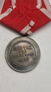 Dansk Røde Kors Fortjenstmedalje, som blev indstiftet i 1927 og tildeles for fortjenstfuld indsats for Røde Kors. Original