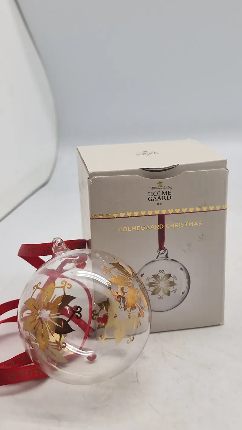 Holmegaard Christmas årets julekugle 2024, designet i klart glas med guld- og røde detaljer