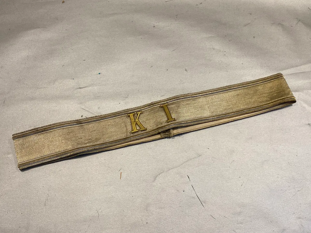 Kasketbånd med isatte metalbogstaver “KI”