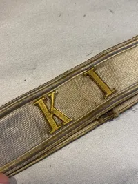 Kasketbånd med isatte metalbogstaver “KI”