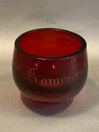 Mundblæst rødt glas med teksten “Skaal Kammerater!”