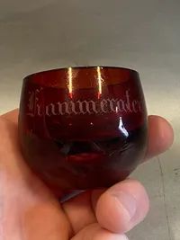 Mundblæst rødt glas med teksten “Skaal Kammerater!”