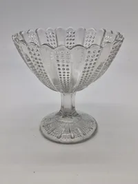 Sukkerskål presset med mønster af skiftevis stråler og små prikker. Sukkerskålen med tunget kant og "facetslebet" stilk. 
Kastrup Glasværk 1886