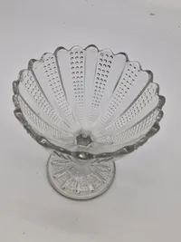 Sukkerskål presset med mønster af skiftevis stråler og små prikker. Sukkerskålen med tunget kant og "facetslebet" stilk. 
Kastrup Glasværk 1886