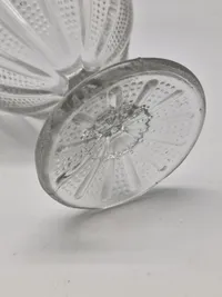 Sukkerskål presset med mønster af skiftevis stråler og små prikker. Sukkerskålen med tunget kant og "facetslebet" stilk. 
Kastrup Glasværk 1886