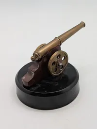 Miniature messingkanon på sort rund sokkel