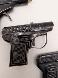 Tre antikke legetøjspistoler i metal, herunder O'les mains og D.R.G.M.