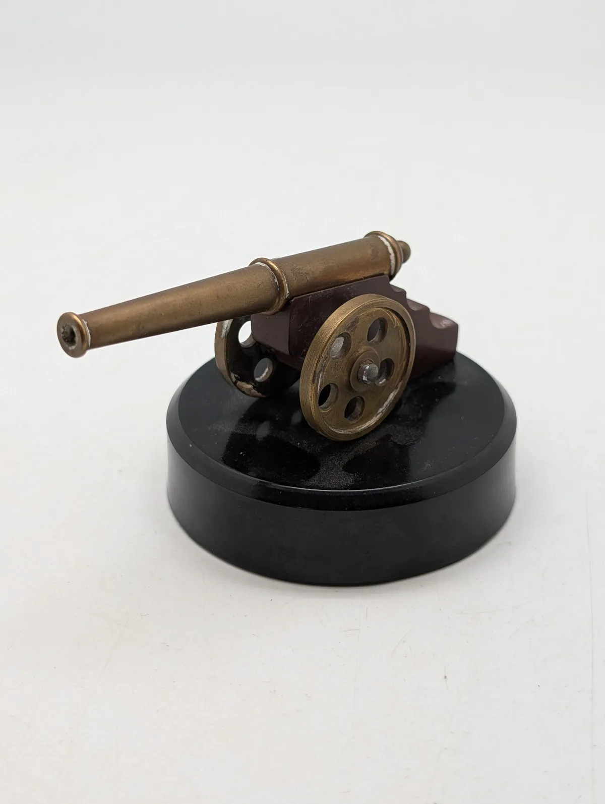Miniature messingkanon på sort rund sokkel