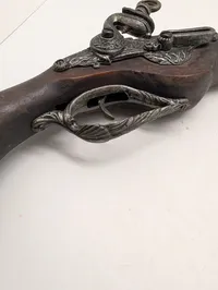 Dekorativ flintlåspistol i træ og metal med ornamenterede detaljer