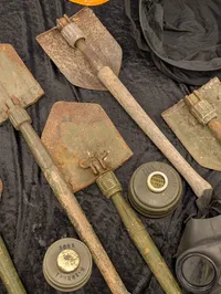Militært udstyr med feltspader, gasmasker og hjelm