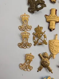 Samling af danske militære kasketemblemer og korpsmærker i messing