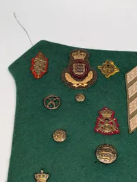 Samling af danske militære distinktioner og emblemer på grønt filt