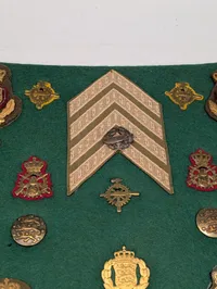 Samling af danske militære distinktioner og emblemer på grønt filt