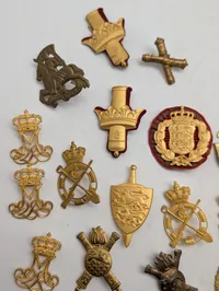 Samling af danske militære kasketemblemer og korpsmærker i messing