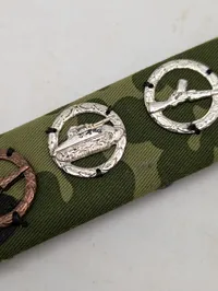 Militær bånd med fire færdighedstegn på camouflagebund