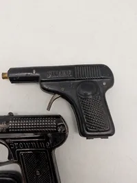 Tre antikke legetøjspistoler i metal, herunder O'les mains og D.R.G.M.