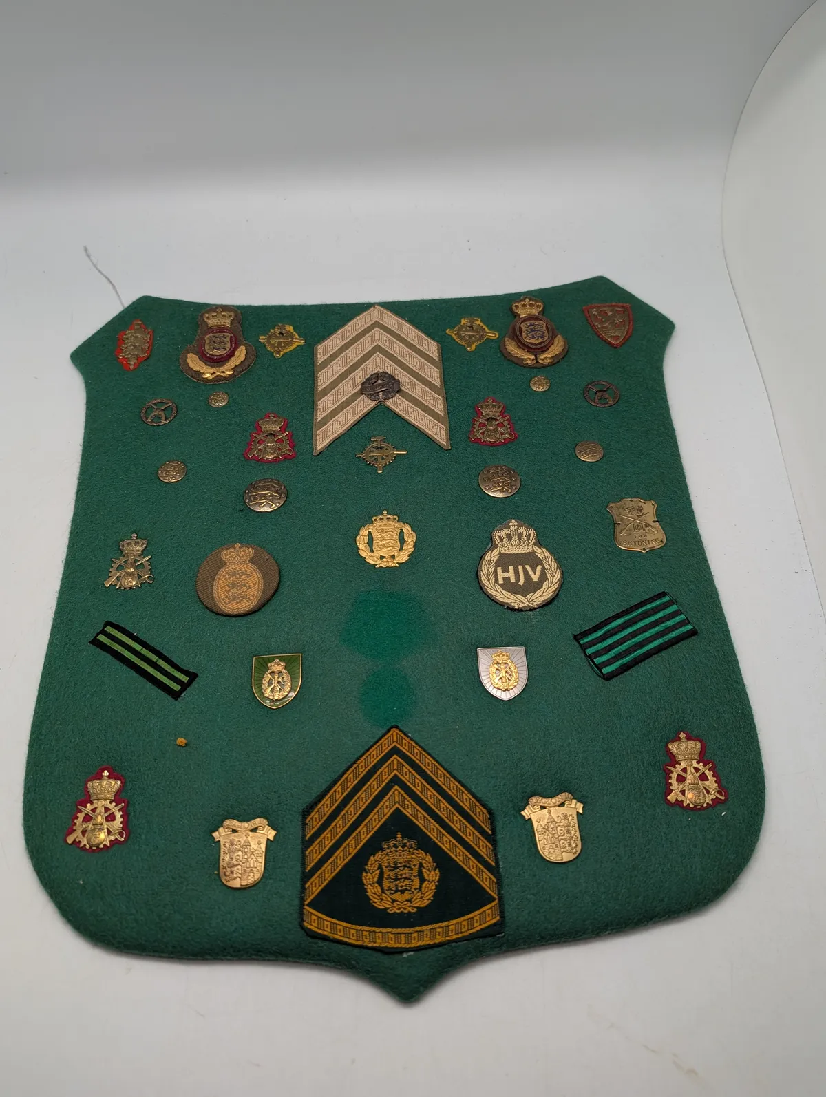 Samling af danske militære distinktioner og emblemer på grønt filt