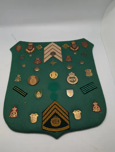 Samling af danske militære distinktioner og emblemer på grønt filt