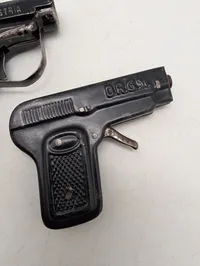 Tre antikke legetøjspistoler i metal, herunder O'les mains og D.R.G.M.