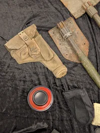 Militært udstyr med feltspader, gasmasker og hjelm
