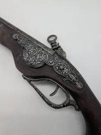 Dekorativ flintlåspistol i træ og metal med ornamenterede detaljer