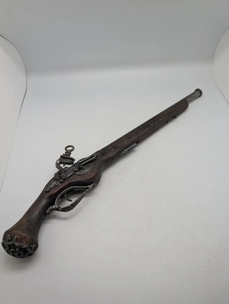Dekorativ flintlåspistol i træ og metal med ornamenterede detaljer