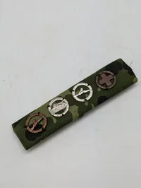 Militær bånd med fire færdighedstegn på camouflagebund