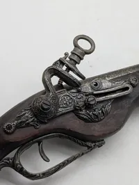 Dekorativ flintlåspistol i træ og metal med ornamenterede detaljer