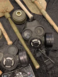 Militært udstyr med feltspader, gasmasker og hjelm
