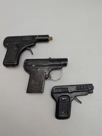 Tre antikke legetøjspistoler i metal, herunder O'les mains og D.R.G.M.