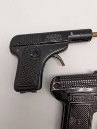 Tre antikke legetøjspistoler i metal, herunder O'les mains og D.R.G.M.