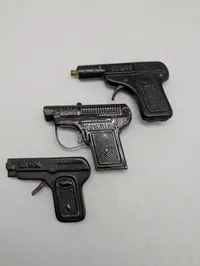 Tre antikke legetøjspistoler i metal, herunder O'les mains og D.R.G.M.