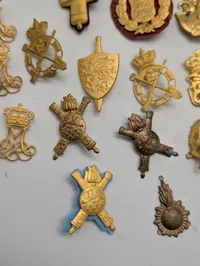 Samling af danske militære kasketemblemer og korpsmærker i messing